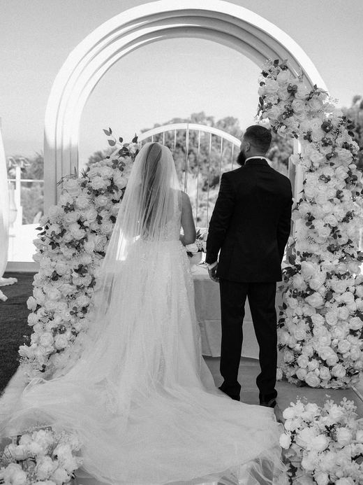 The couple at the white rose arch, seen from behind