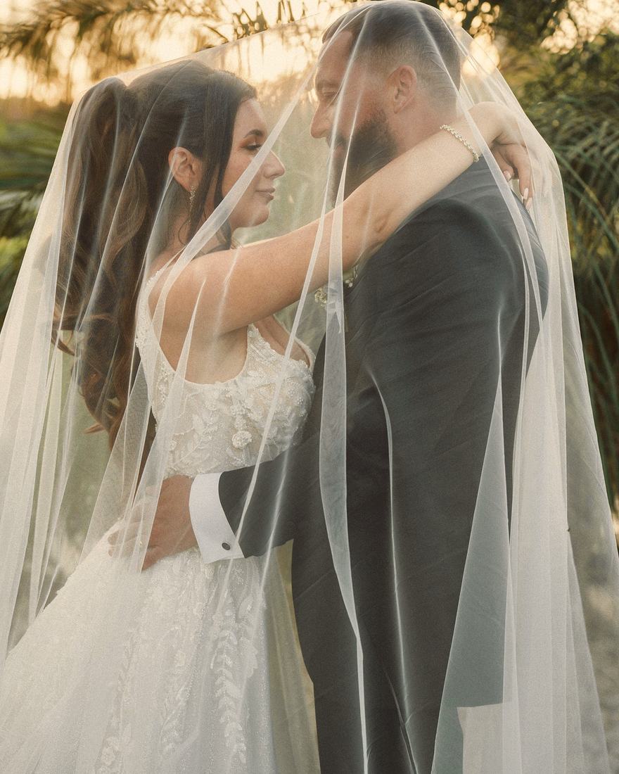 A couple under the veil among the palms at the Omega Mansion